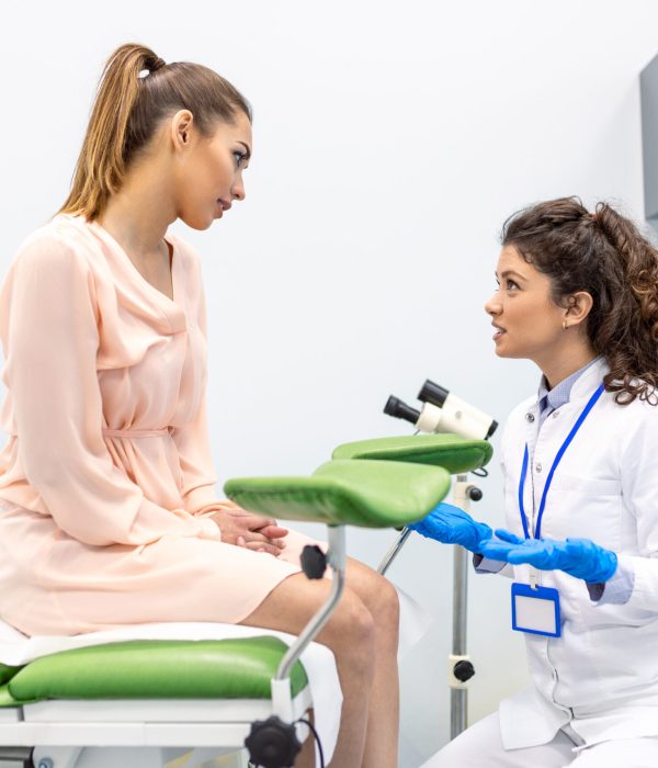 Gynecologist preparing for an examination procedure for a pregnant woman sitting on a gynecological chair in the office